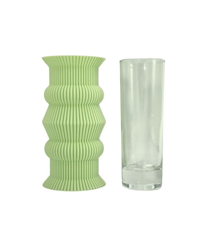 Un vaso verde lime con texture rigata, affiancato da un bicchiere di vetro trasparente per confronto dimensionale.