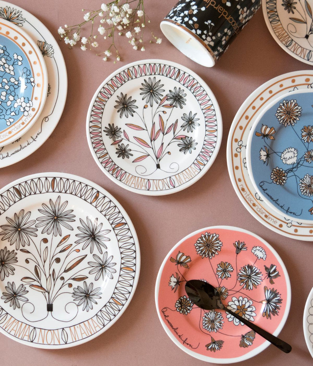 Tavola apparecchiata con piatti in porcellana decorati con motive floreali e scritte che celebrano l'amore