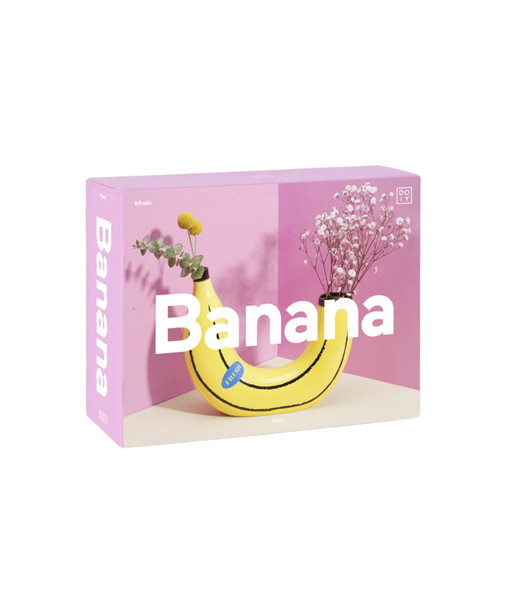 Confezione del Vaso Banana, che mostra l'immagine del vaso a forma di banana gialla con fiori gialli e bianchi, su uno sfondo rosa.